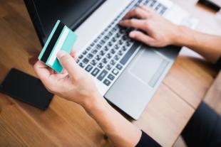 Person holding credit card in front of laptop